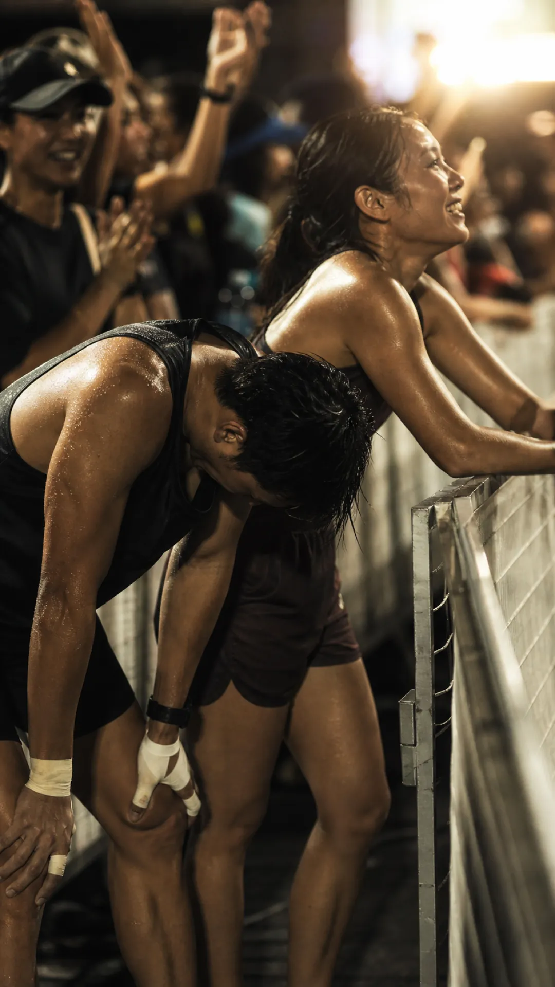 An exhausted athlete leans on a barrier after the finish