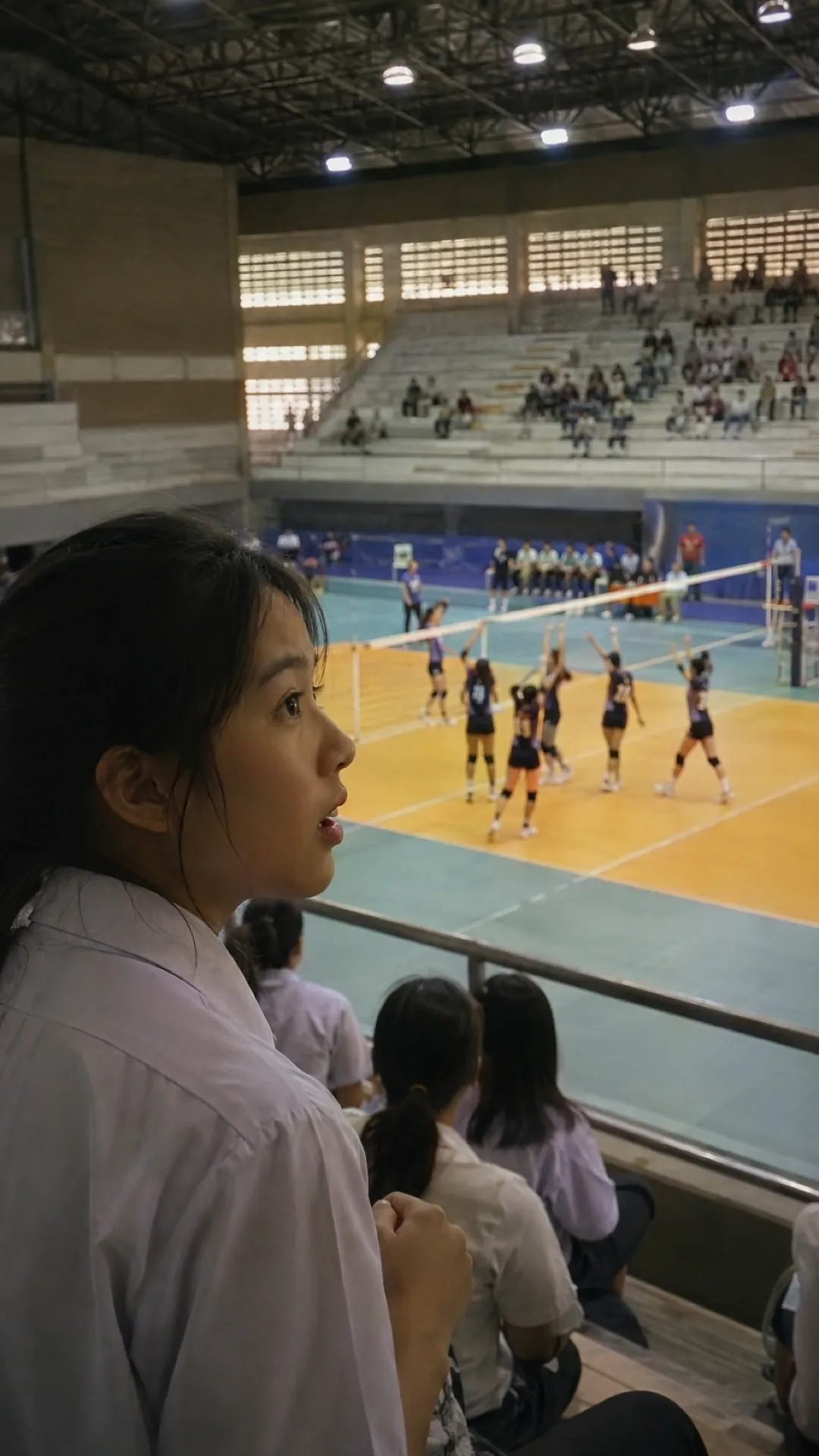 A girl watches a school match from the side of an indoor court
